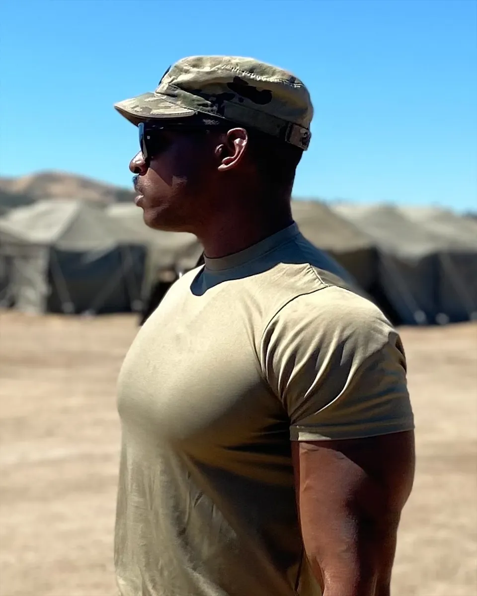 Coach Venchie in his Army uniform, standing in front of field tents